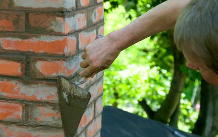 Trowel making its pass along raked brick joints